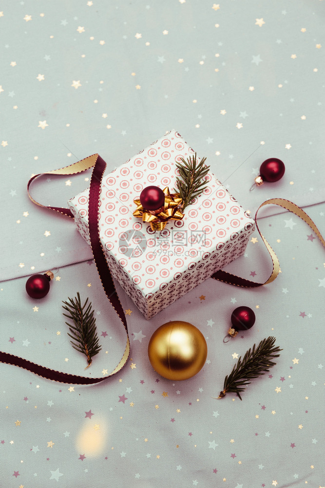 平坦的包裹最佳用红丝带圣诞球和松树枝织物将圣诞礼包成装饰盒品在背景中粉红色布料模糊了圣诞节的灯光图片
