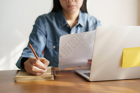 人们写作亚裔妇女在办公室用铅笔写记商业妇女工作士图片