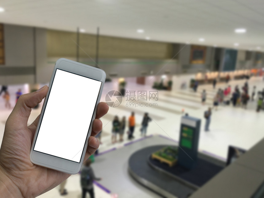 航班手持智能电话空白屏幕的男子在机场上模糊等待行李背景的飞机布料国际大厅图片