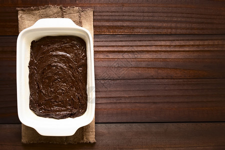 用油粉和面烘烤锅用天然光照在黑木头上方的相像照片土制粗面包或巧克力蛋糕饼面团甜点平底锅质地背景图片