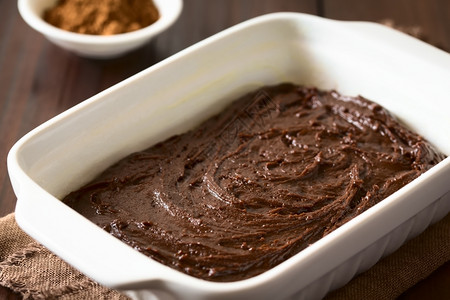 或者棕色的生基本自制布朗尼或巧克力蛋糕面团用油粉和烘烤锅糊贴在黑木上以自然光拍攝选择焦点图像聚三分之一背景图片