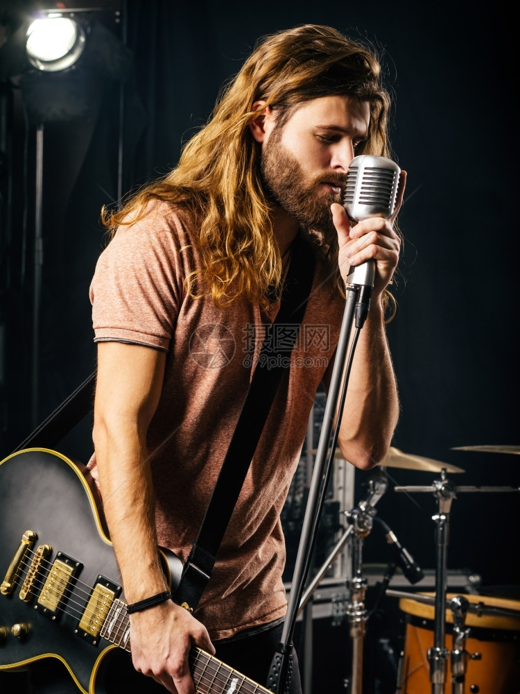 优质的摇杆一位长头发胡子的年轻人在舞台上唱歌和演奏电吉他的照片笑声岩石图片