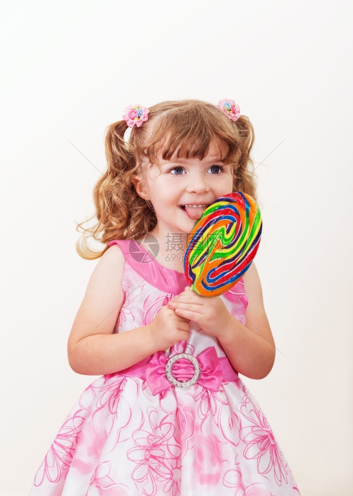 丰富多彩的糖果可爱小女孩的肖像和彩色大棒糖在光背景上清白的图片