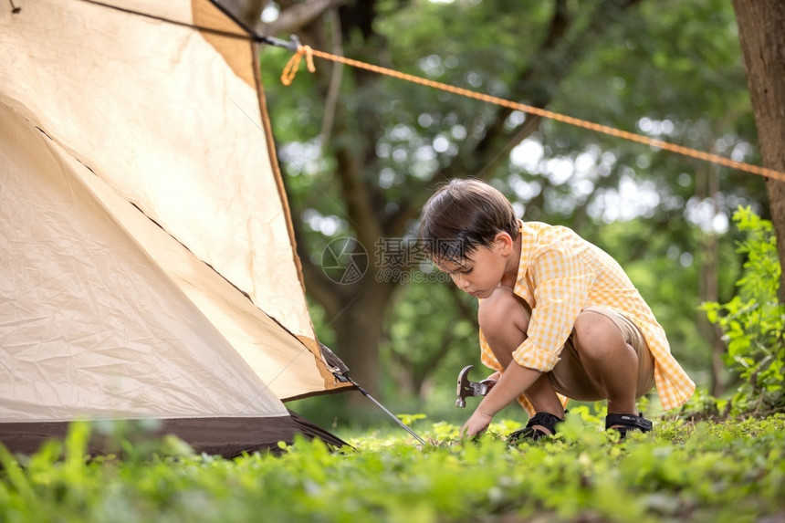 帮助可爱的持锤子男孩周末在草地上林中搭建帐篷男生图片