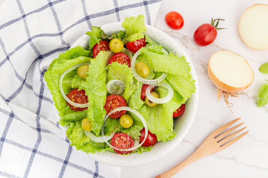 一顿饭叉新鲜和健康的沙拉配有生菜洋葱樱桃番茄和在地中海食物碗的橄榄盘子图片