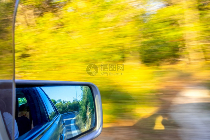 汽车在一条夏季公路上快速行驶道路标志和灌木在后视镜的中阳光天气一种反射空图片