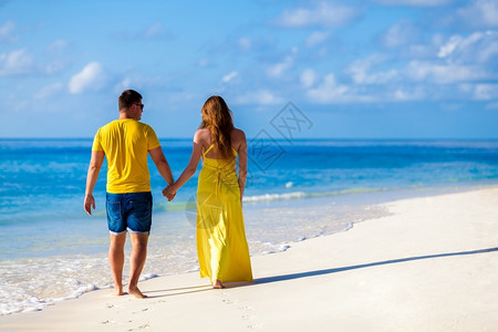 马尔代夫一对妇在海滩上散步蜜月白色的蓝图片