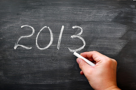 木板用过的2013年用粉笔写在一张涂满黑板的粉笔纸上手握着粉笔教图片