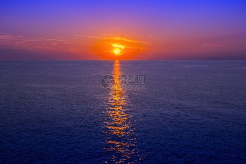 超过美丽的黎明日落在海面上以水中反射为背景图片