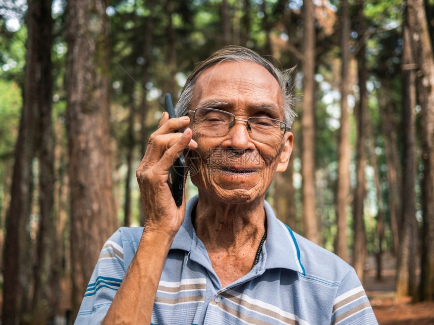 男在花园里使用智能手机的亚洲老年男子外部陈图片