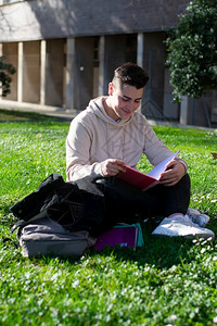 青年坐在学校草地上看书图片