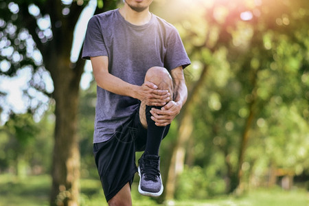 男子在运动前伸展腿部肌肉年轻男运动员参加训练阳光跑步人们图片