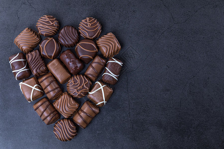 甜点巧克力糖果堆积如心状的巧克力糖黑色背景关注巧克力天黑暗的图片
