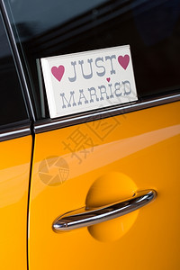 婚姻新人键夫妇在他的橙色汽车里旅行度蜜月图片