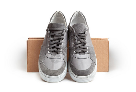 活动锻炼灰色零散运动鞋在白色背景的棕纸板盒上被孤立的滑鞋网球图片