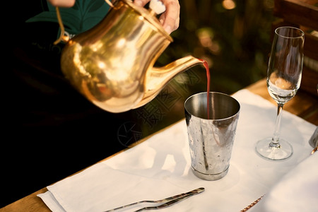 酒商把精汽水倒进一杯子里在酒吧柜台上加甜红莓鸡尾酒玻璃专业的威士忌酒图片