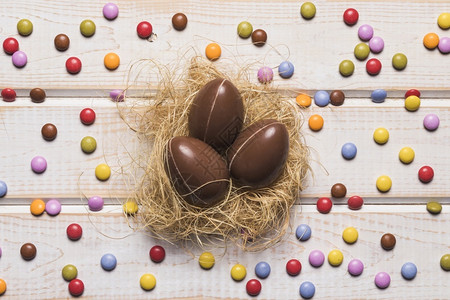 安全的维他命业务围绕巧克力东鸡蛋巢木桌周围的彩色宝石糖果图片