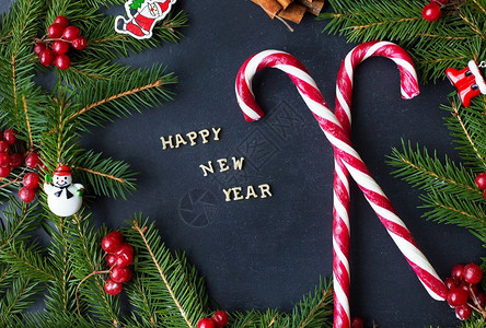 糖果装饰素材框架一种圣诞树有装饰品和糖果在黑色背景上刻着新年快乐圣诞树刻着首饰和糖果在黑色背景上刻着新年快乐的标志红色背景