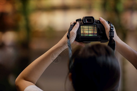 年轻摄影女青提高像头的将照片选择焦点放在相机上颜色散景专业的图片