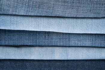 折叠蓝色牛仔裤堆背景或纹理牛仔布衣柜图片