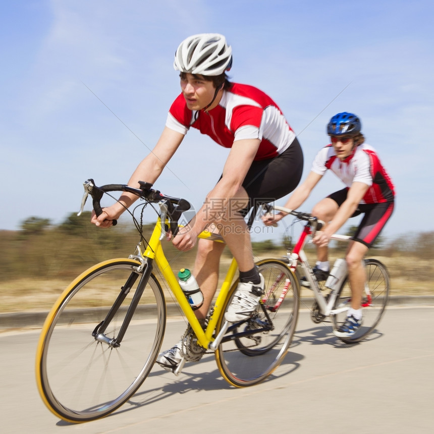 两名骑自行车的人高速冲过摄影机刺耐力运动员图片