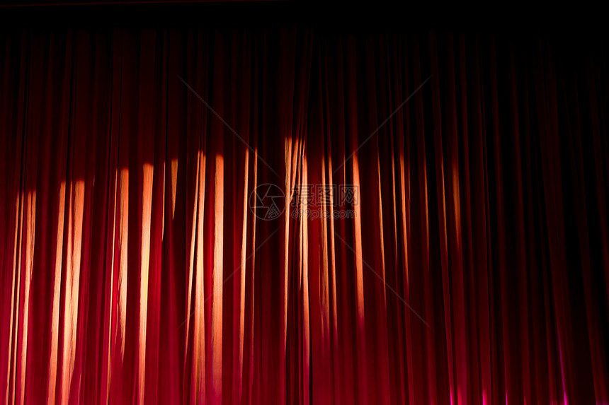 红色的经典演戏红窗帘和两场表演之间戏院的聚光灯图片