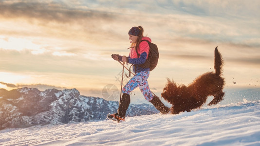 可爱的太阳乐趣鸟女孩和她的狗在冬季漫步雪中玩耍图片