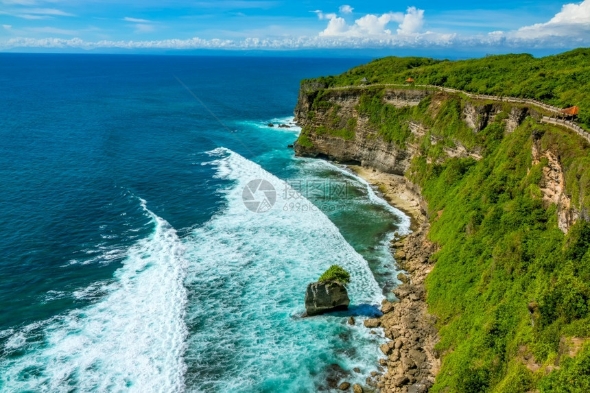 印度尼西亚海洋上阳光明媚的天气和地平线上的云层沿着阿尔布山顶的岩石热带海岸沿途道落基热带海岸和阿尔布与的预兆海岸线最佳多岩石的图片