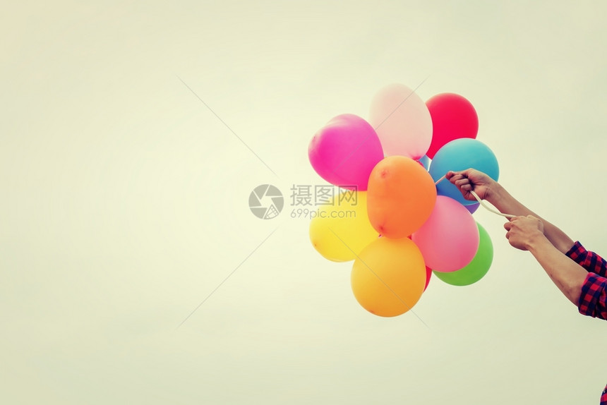 一个十几岁女孩手握着阳光中的彩色气球一个十几岁女孩手握着夏天的阳光中彩色气球细绳简单复古的图片