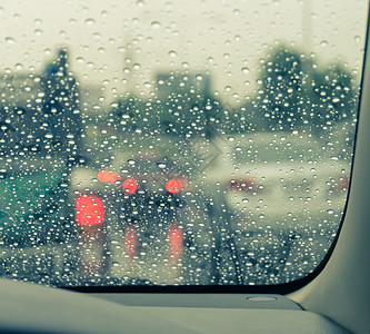 过滤湿的路在雨天风屏上看到蓝色驾驶车经过湿挡风玻璃图片
