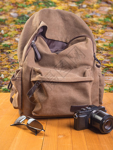 指导游客秋叶背景的包相机和太阳镜秋叶背景的旅游包相机和眼镜电话图片