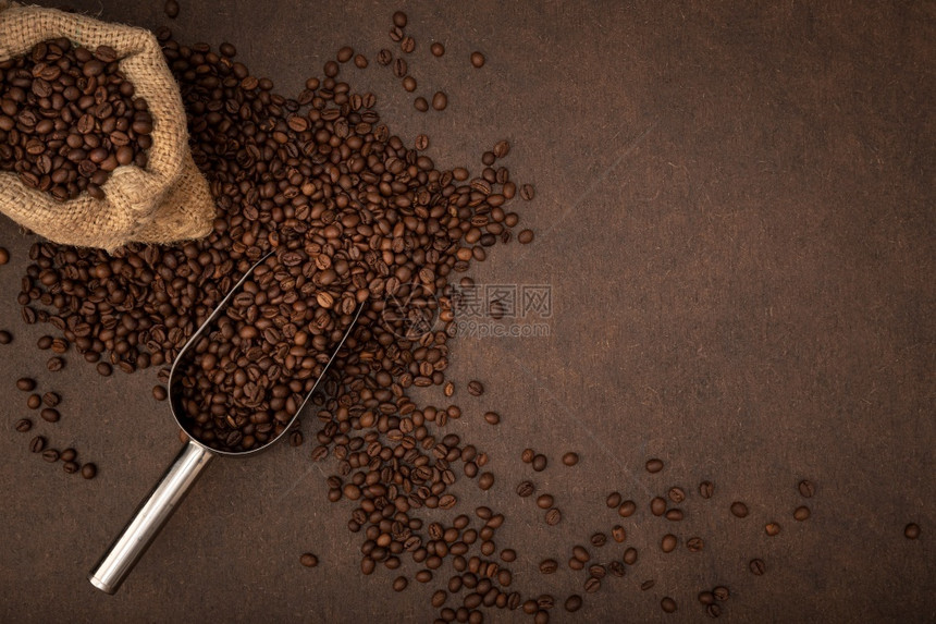 袋装咖啡豆和棕色背景里的勺子图片