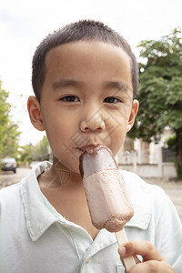 快乐的奶油近距离面对亚洲男孩吃巧克力冰淇淋和快乐面孔童年戳高清图片素材