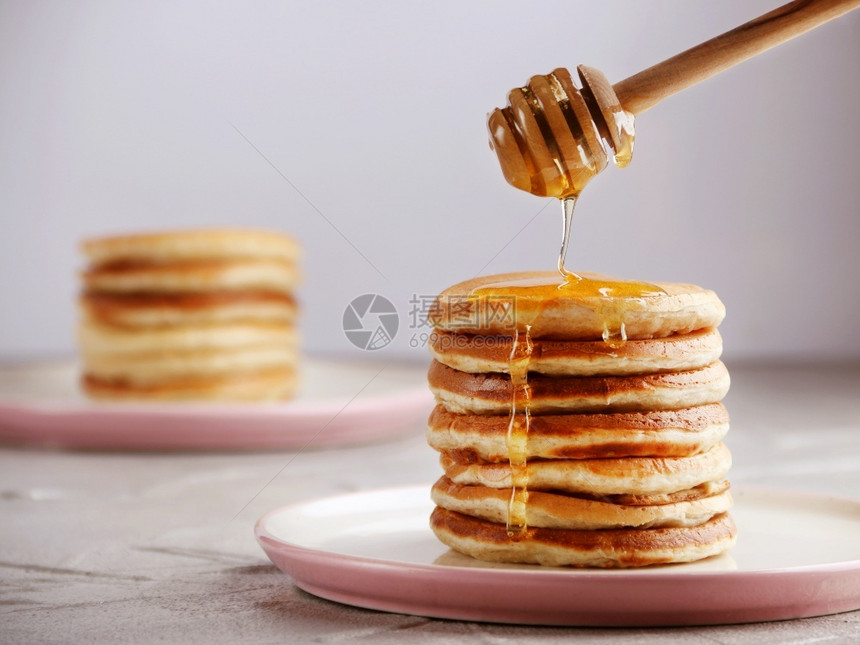 堆满煎饼和蜂蜜勺子将倒在轻便的背面用蜂蜜勺子把倒在光背景上薄煎饼早餐营养图片