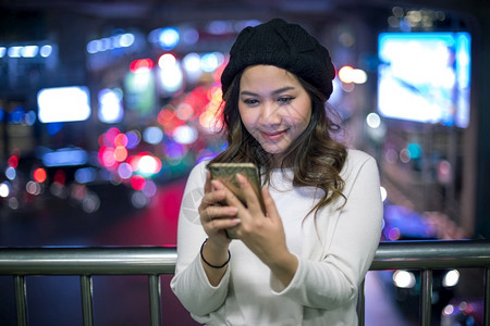 聪明的游客街道美丽年轻亚洲女在夜间使用手机的户外肖像画女青年图片