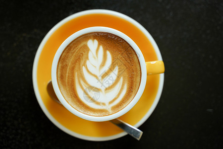 咖啡师艺术黑桌上的咖啡拿铁叶图案早餐背景图片