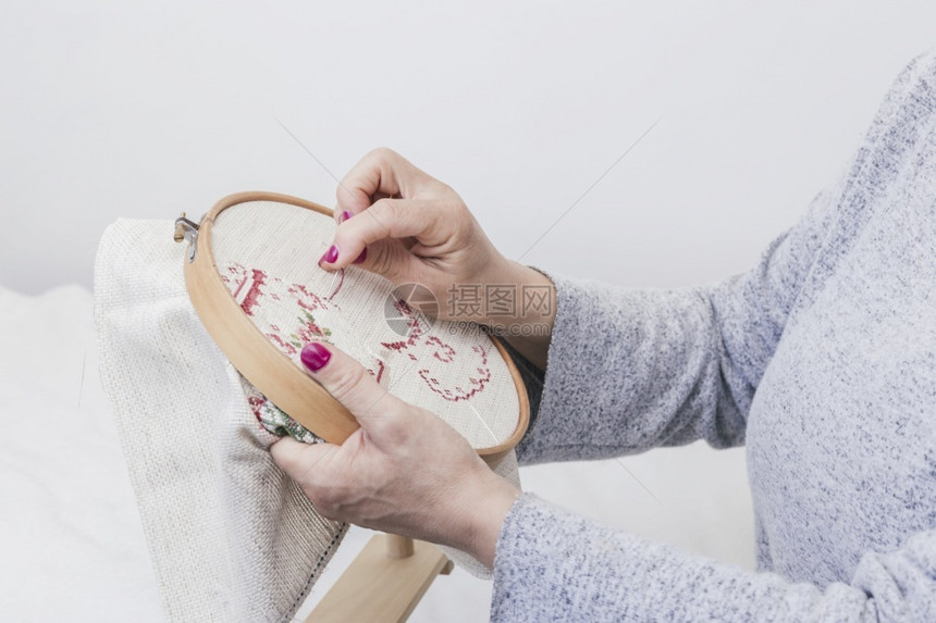工艺闲暇手制作的s妇女用手在白色背景的环圈上交叉缝合模式图片