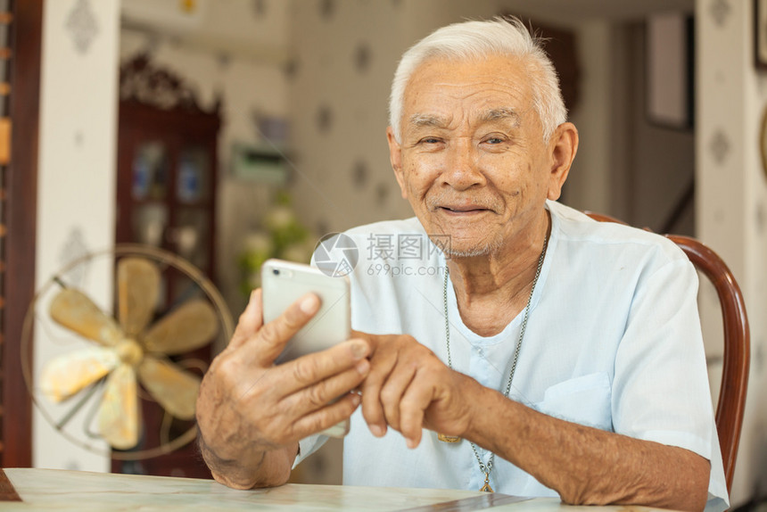 坐在客厅桌子上玩手机的老年人图片