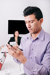 一名商人用手机坐在办公桌的旁成功人黑发图片