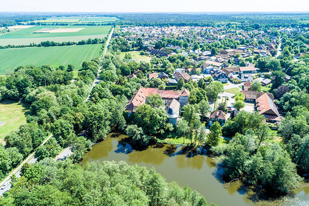 屋在沃尔夫斯堡附近一个拥有小森林池塘和地表浅色城堡的德国村庄空中景象观房屋背景