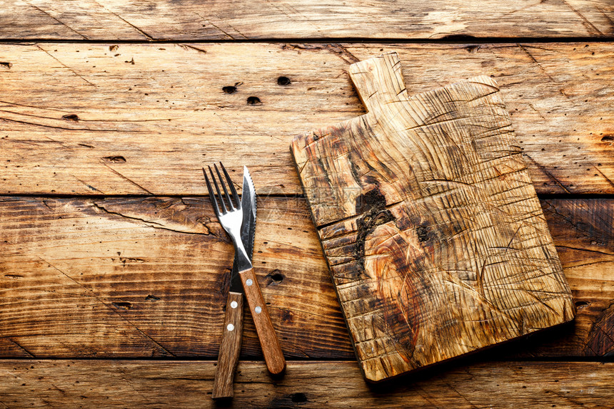 空白的食物背景空切割板上摆着一把刀和叉子放在生锈的木制桌子上从顶部看复制空间自然图片