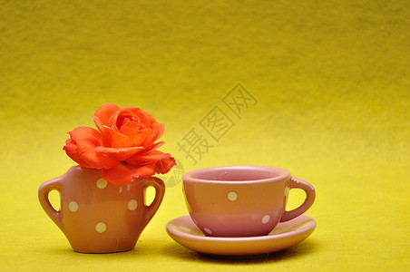锅黄色背景的茶杯和橙色玫瑰空的饮料图片