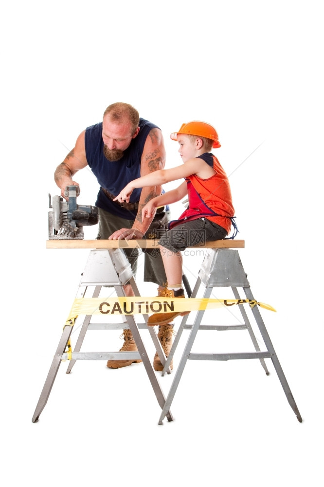 教可爱儿子正在帮助爸砍木板当他指出如何操作时用重值勤圈锯开木板孤立的男孩坐在木板上指着圆边看到父亲在使用木头职的图片