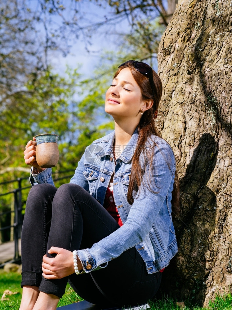 一位美丽的年轻女子在喝咖啡时享受清春初日的温暖和阳光照像萨姆纳斯闲暇早期的图片