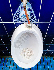 老的管道撒尿公共洗手间中带有青蛙球的肮脏小便池水高清图片素材