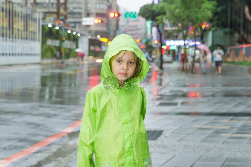 微笑城市穿着绿色雨衣在市街旁边淋雨的年轻女孩街道图片