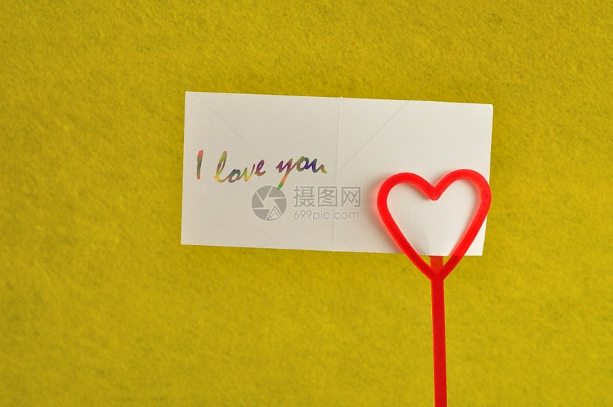 快乐的象征浪漫白日情人节一个红心的记号持有者带着一张字条念著我爱你在黄色背景下被孤立图片