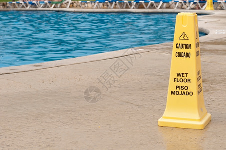 游泳池旁边滑地表面的黄色警示符号图片