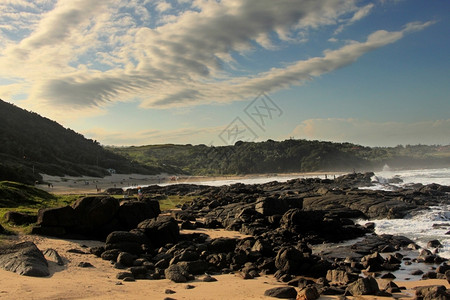 海景白云和蓝天与黑岩海滩的照片滨溅起图片