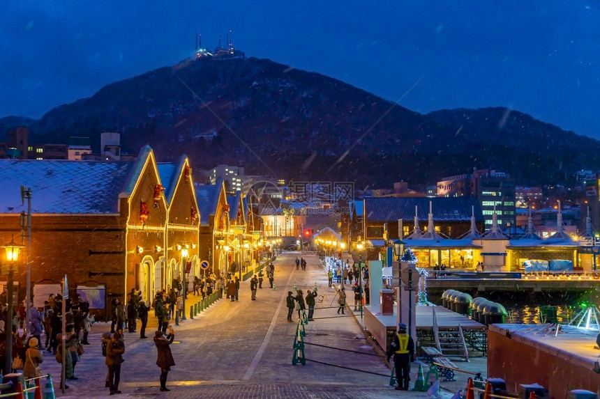 雪日本人古老的红砖仓库和冬季日本北海道Hakodate黄昏时Hakoate山的城市风景建造图片